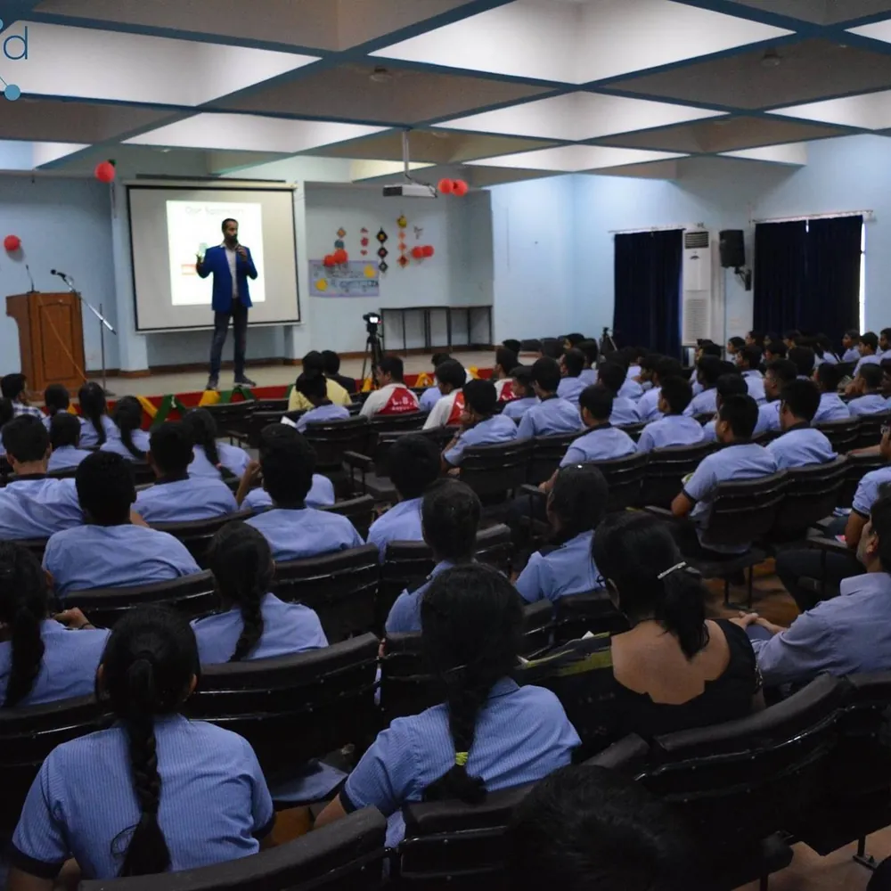 Gaurav on stage speaking to a large hall of students
