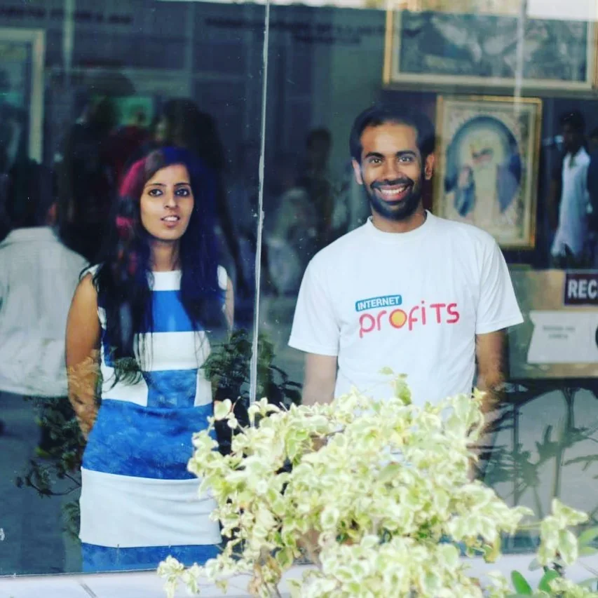 Photo: Gaurav in an Internet Profits T-shirt beside Roshni Dhal, seen through a glass shopfront